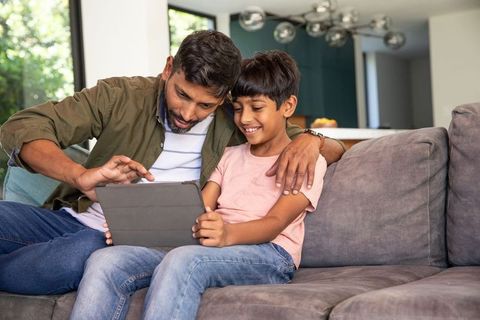 Father and Son Enjoying Tablet on Sofa in Modern Living Room