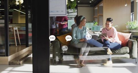 Colleagues Analyzing Data on Tablet in Modern Office Lounge