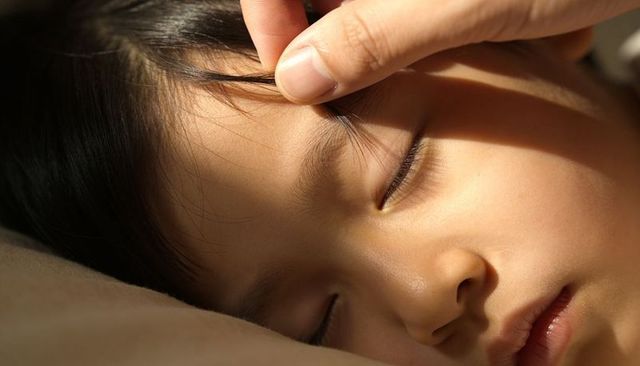 Closeup sleeping child with gentle hand lifting hair warm cozy bedtime caregiving moment