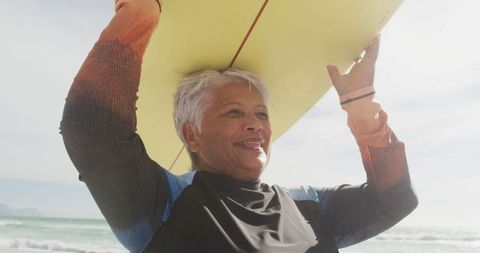 Senior Woman Joyful with Surfboard on Beach During Retirement