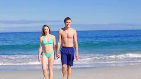 Joyful Couple Strolling Hand in Hand on a Scenic Beach