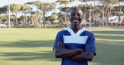 Confident Footballer Smiling on Sunny Soccer Field