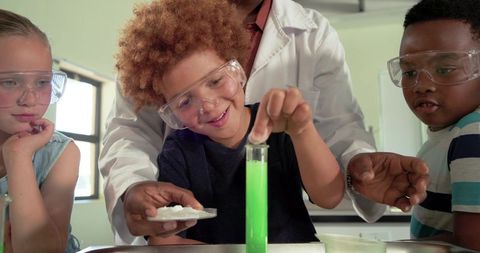 Children conducting glowing chemistry experiment with teacher guiding in classroom science lab