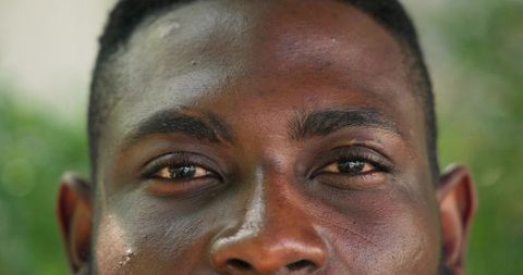 Close-up gazing african american man showing natural skin texture with green bokeh
