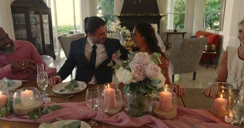 Newlywed Couple Laughing with Friends at Wedding Reception Table