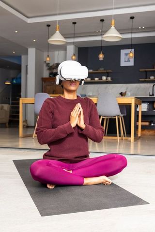 Woman meditating wearing vr headset in modern open-plan kitchen for virtual mindfulness