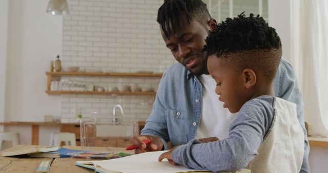 Scene of an African American man engaged in teaching a young boy at home. Ideal for illustrating concepts of home education, mentoring, family bonding, and personalized tutoring. Can be used in educational blogs, parenting websites, and promotional materials for tutoring services.