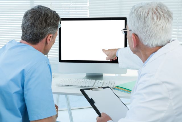 Surgeon and doctor discussing over personal computer in clinic