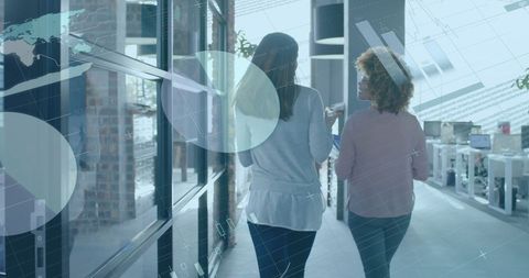 Businesswomen Walking in Office with Financial Data Overlay
