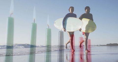 Surfers walking along beach with overlay of vibrant candles