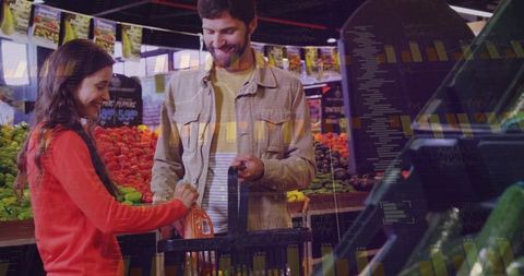 Smiling couple shopping for fresh produce placing packaged carrots into grocery cart