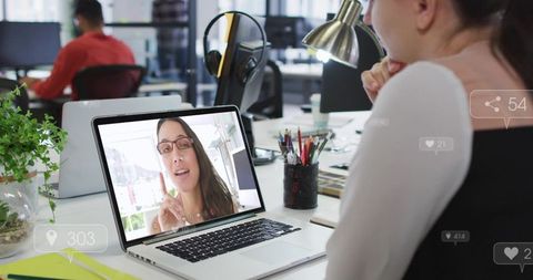 Remote team member joining video call on laptop at collaborative open-plan office desk