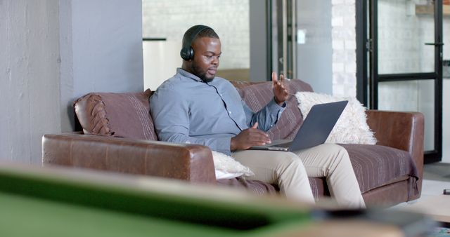 Man Wearing Headphones Working on Laptop from Couch - Download Free Stock Images Pikwizard.com