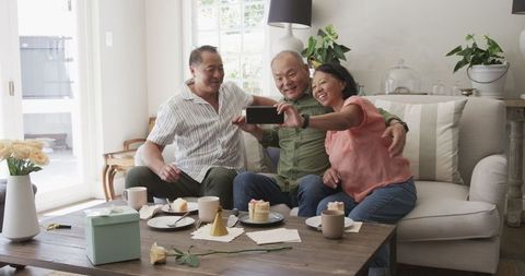 Asian Seniors Sharing Warm Moments Over Coffee and Cake