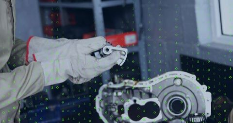 Mechanic inspecting bearing wearing white gloves with gearbox and green binary overlay