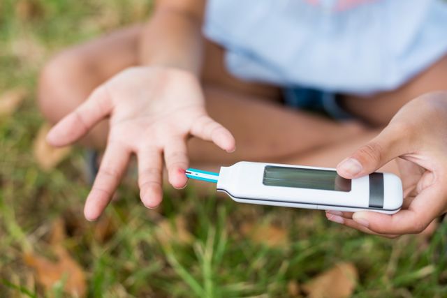 Girl testing diabetes on glucose meter in park