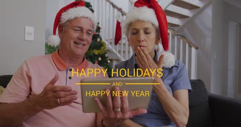 Senior couple celebrating holidays with santa hats using digital tablet