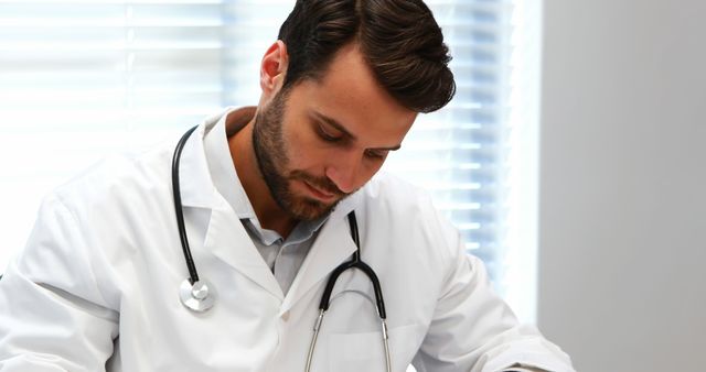 Focused Doctor Writing Patient Notes in Modern Clinic - Download Free Stock Images Pikwizard.com