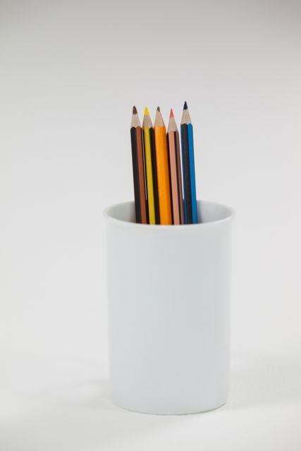Colored pencils kept in cup on white background