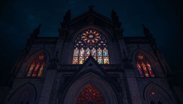 Gothic cathedral facade glowing at night with illuminated rose window
