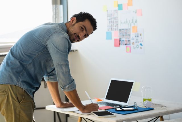 Side view portrait of young man working at desk in creative office