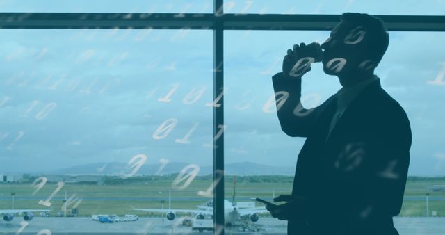 Businessman drinking coffee while looking at cellphone and standing by window at airport. Ideal for use in articles or advertisements related to business travel, airport lounges, travel technology, professional routines, or global transportation.