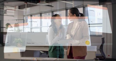 Women discussing work while holding tablet in modern open-plan office with UI overlays