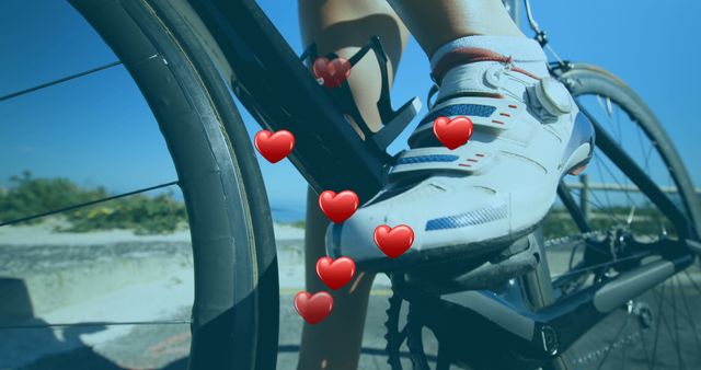 Close-up of a cyclist's foot pedaling a road bike with heart graphics overlaid, representing health or fitness. Useful for promoting cycling events, health, wellness, and active lifestyle content.
