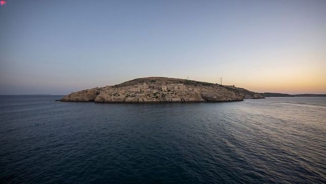 Dawn seascape panorama of rocky isle with limestone cliffs, abandoned buildings and antenna