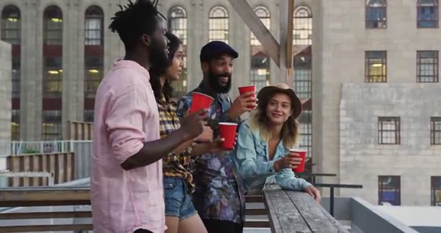 Young, enthusiastic individuals savor lively urban atmosphere, clutch informal party set-up. Ideal for promoting themes of friendship, social events, summer celebrations, or rooftop parties. Perfect for advertising nightlife or community events in diverse city settings.