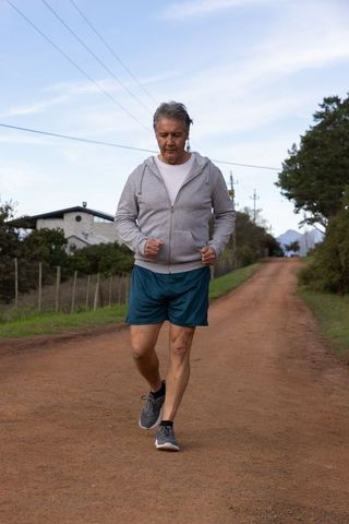 Middle-aged Man Jogging on Scenic Rural Pathway in Activewear