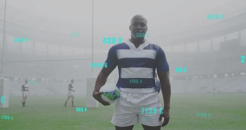 Rugby player standing and holding ball on misty stadium pitch with teal data overlays