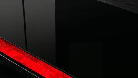 Crimson led strip cutting diagonal across glossy black panel with reflective seam