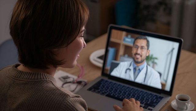 Woman engaging in online consultation with doctor on laptop at home