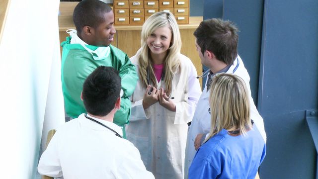 Group of healthcare professionals having a friendly and positive discussion within a hospital setting. Suitable for themes related to teamwork in healthcare, medical staff collaboration, and professional interactions in medical environments. Great for articles on healthcare collaboration, medical team conferences, or educational materials for medical training.