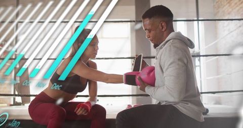 Female boxer training with coach in boxing ring throwing pink glove during coaching session