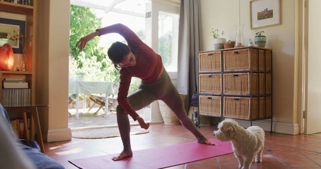 This scene shows a young woman in an indoor setting, practicing yoga on a mat with her pet dog observing curiously. Suitable for illustrating topics related to home fitness, healthy living, mindful practices, and the bond between pets and their owners.