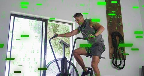 Riding air bike in home gym with green binary overlay for high-intensity cardio training