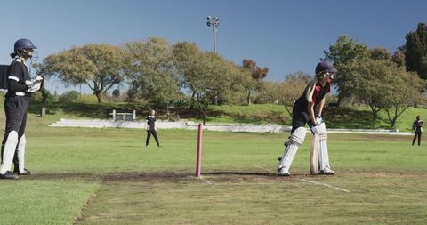 Female cricket players practice on sunny day, focus on batting and wicketkeeping