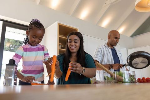 Diverse family preparing healthy meal together in bright modern kitchen