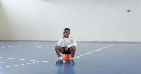 Determined Boy with Basketball Reflecting on School Court