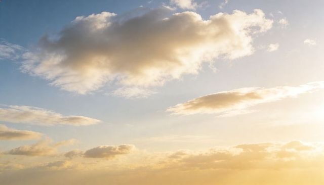 Golden-hour cumulus cloud glowing over expansive sky with soft low cloud band, warm light