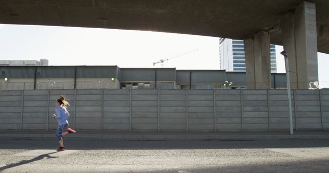 Woman Jogging Under Urban Overpass with Modern Buildings - Download Free Stock Images Pikwizard.com