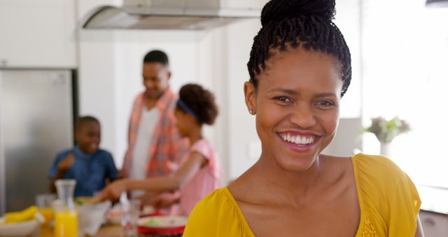 Front view of happy mid adult black woman looking at camera in a comfortable home. Father and children standing at dining table 4k