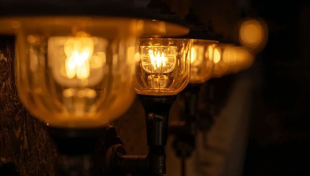 Vintage industrial glass-shade wall lamps with glowing filament bulbs and warm amber bokeh