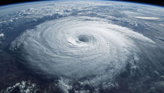 Orbiting hurricane eye revealing massive spiral bands over ocean and coastal terrain