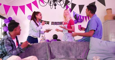 Multiracial friends celebrating birthday in festive living room