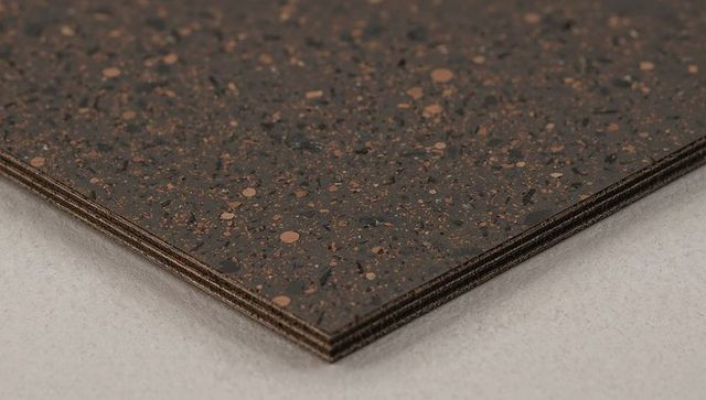 Stacked speckled composite sheets with copper flecks layered plywood core texture closeup