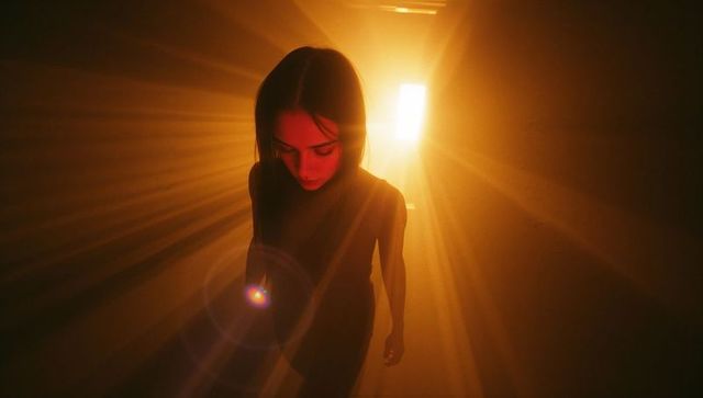 Woman Walking Towards Light in Corridor with Dramatic Lens Flare