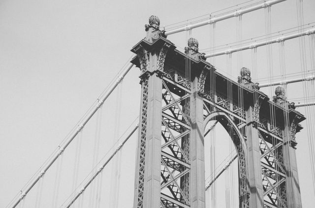 Close-up of detailed architecture of an iconic bridge in black and white. Emphasizes engineering and structure. Suitable for projects related to urban development, historical landmarks, engineering feats, architectural studies, transportation, and travel inspiration.